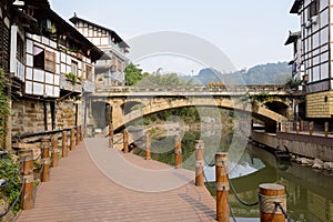 Waterside planked path before aged bridge in ancient town