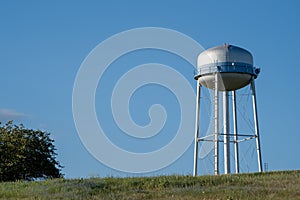 Watertower in a field against a blue sky photo