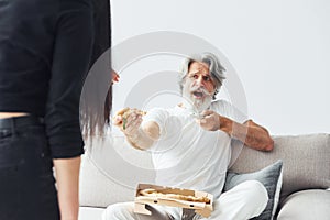 Wathing TV with scary woman with black hair near him. Senior stylish modern man with grey hair and beard indoors