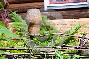 Wattle fence with old clay pot and log house