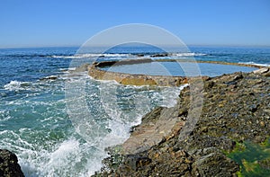 Wave action meets the rocky shoreline at Victoria Beach in Laguna Beach, California.