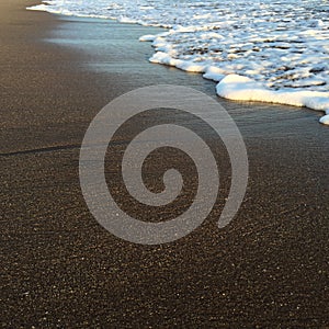 Wave and beach, shiny tropic sea wave on the beach sand in sunset light