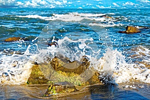The wave beats against the rock and spreads out with splashes.