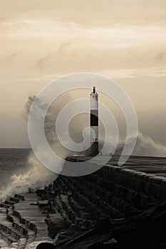 Wave breaking on jetty and beacon during storm at Aberystwyth in Wales.