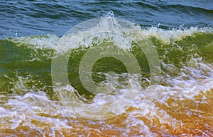 Wave breaking over blue swells crashing curling a surface