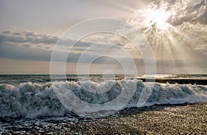 Wave breaking on pebble sea shore at sunset. Scenic landscape at Khosta beach, Sochi, Russia