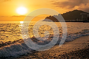 Wave breaking on pebble sea shore at sunset. Scenic landscape at Khosta beach, Sochi, Russia