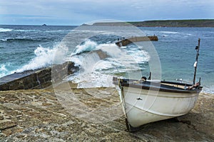 Wave breaking on Sennen cove fishing harbor breakwater