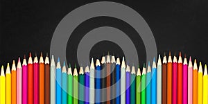 Wave of colorful wooden pencils isolated on a black background, back to school concept photo