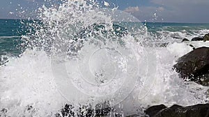 The wave crashes against black stones sea ocean