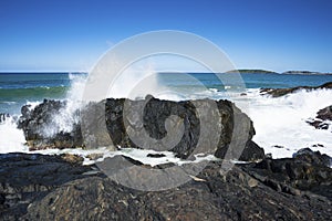 A wave crashes against the rocks at Macauleys Headland