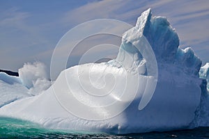 Wave crashing against large iceberg marooned near the coast