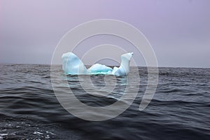 Wave crashing against small iceberg bit floating in sea