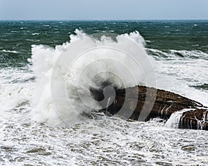 Wave crashing on rock by a stormy day