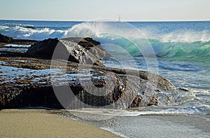 Wave crashing on rocks at Aliso Beach in Laguna Baech, California.