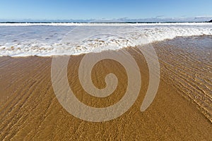 Wave laps a golden sand beach