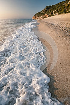 Wave at Milos beach at sunset near the Agios Nikitas village on Lefkada Ionian island, Greece. Evening golden light