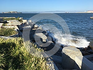 The Wave Organ with spray up along the walk with Alcatraz Island in the back left.