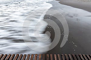 Wave rolls ashore, long exposure black and white photography