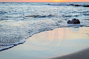 Wave of the sea on the sand beach. Seashore on sunset