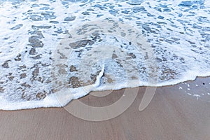 Wave of the sea on sandy beach white foam.Top view of a wave breaking on the sand at the beach. Top view,Copy space