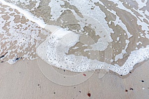 Wave of the sea on sandy beach white foam.Top view of a wave breaking on the sand at the beach. Top view,Copy space