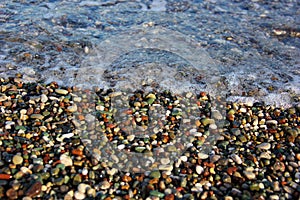 Wave from the sea tends to small colored pebbles