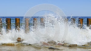 Wave on the seashore crashes on wooden breakwaters