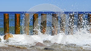 Wave on the seashore crashes on wooden breakwaters