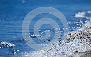Wave splash of the water in the sea with specks and reflections during high tide time, abstract background or texture. Water