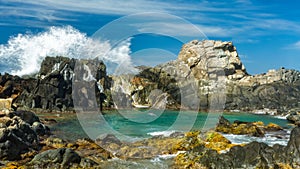 Wave splashes against rocks in Aruba