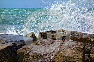 Wave spray againts rocks at sea ocean