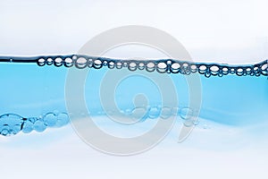 Wave of transparent liquid with bubbles, cosmetic essence close-up