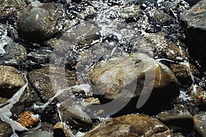 A wave washes the rocks near the shore. Sea stones.