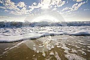 Wave washing up the sand at sunset