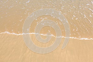 Wave of water on clear golden sandy beach