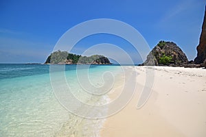 Wave on white fine sandy sand & shallow blue water with speed boat & cloudless sky at Pulau Lima Besar island, Johor, Malaysia photo