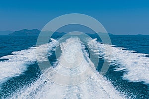 Waves on blue sea behind the speed boat with mountain and sky.