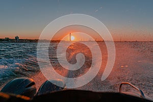 Waves on the blue sea behind the water of a speedboat with bright sun, sunny sunset