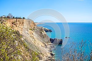 Waves of blue sea splashing on the sand-colored cliffs.