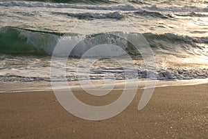 Waves of the blue sea splashing on the sandy shore.