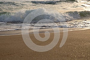 Waves of the blue sea splashing on the sandy shore.