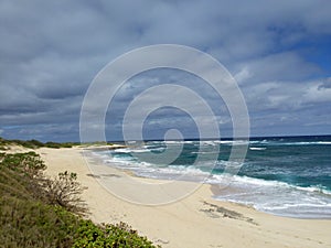 Waves break and crash towards the Hanakailio Beach with dramatic blue-pink cloudy skyline at dusk