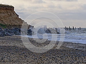 Waves break on rocks protecting soft cliffs from erosion