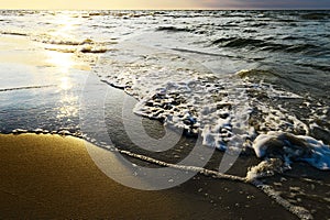 Waves breaking on the beach at sunset.