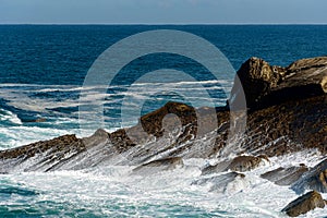 Waves breaking and forming sea foams on rocks