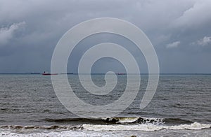 WAVES BREAKING ON THE INDIAN OCEAN WITH CARGO VESSELS ON THE HORIZON