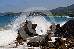 waves breaking onto rocks with a blue ocean behind them photo