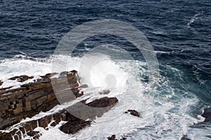 Waves breaking over rocky outcrop along coastline