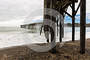 Waves breaking on the poles under the pier of San Simeon, California, USA